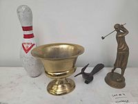Group shot of all four items: bowling pin, brass compote, wood roadrunner, brass golfer