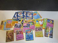 Wide view of approximately 55 Pokémon cards spread out, showing mix of commons, uncommons, rares and holographics