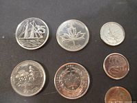 Seven Canadian coins including four 25-cent and three 10-cent pieces on black background