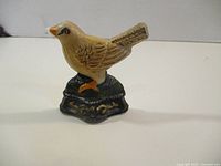 Front view of painted cast iron bird doorstop on decorative base