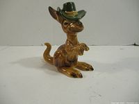 Front view of glazed ceramic kangaroo with green hat