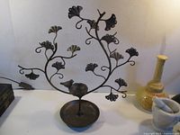 Front view of cast metal tree jewelry stand showing branches, bird figurine and dish