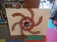 Front view of red metal wall art against background showing full piece and dimensions context