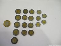 Group of 19 Mexican bimetallic coins arranged on white surface