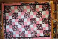 Full view of quilt hanging, showing overall patchwork design and dimensions