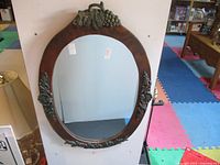 Full view showing oval wood frame and metal grapevine crest
