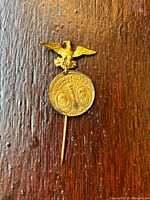 Close up front view of the gold-tone medallion pin depicting eagle and embossed portraits of Henry Hudson and Robert Fulton with event inscriptions.
