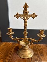 Front view of gold-tone altar crucifix showing detailed crucifix and two candle holders with holy water font base