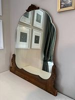 Front view of antique vanity mirror showing shaped glass and carved wood frame