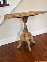 Side view of the antique side table showing scalloped edges and pedestal base.