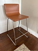 Front-side view of the Ikea Bernhard faux leather bar stool showing the seat and metal sled base.