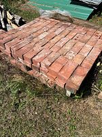 Wide view of stacked red clay bricks arranged on a wooden pallet outdoors