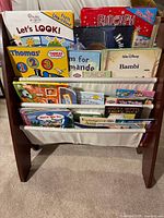 Front view of the wooden book stand filled with children’s books, showing multiple titles and colorful covers.