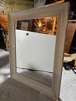 Front view of the rectangular framed mirror with a light wood grain frame and reflective glass surface.