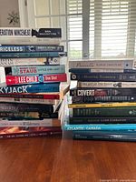 Photo displaying a stacked collection of various hardcover and paperback books, titles include history, fiction, non-fiction, and investigative genres.