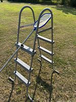 Side view of gray plastic pool ladder with metal handrails