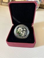 Front side of the 2011 Canadian $10 silver coin showing a group of figures and holly branch.