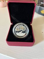 Obverse view of the silver coin in red velvet presentation box, showing a howling wolf under Northern Lights with the year 2014 and $20 denomination.