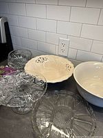 Large ceramic bowls with decorative cutouts and crystal glass serving pieces on kitchen counter