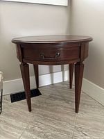 Full view of round wooden side table showing its shape, tapered legs, and fluted apron design