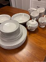 Complete view of Silver Rain ironstone partial dish set including stacked plates, bowls, mugs, creamer and sugar bowl.