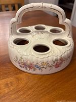 Front view of antique Victorian egg holder showing hand-painted flowers and large handle, six large egg holes.