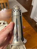 Front view of vintage silver-tone sugar shaker with BTC Hotels branding