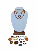 Photo showing entire lot with 3 amber necklaces, 2 bracelets, 1 pin, and assorted amber stones arranged on and around a jewelry bust