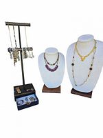 Full view of necklaces displayed on busts alongside bracelets and earrings on stand with drawer
