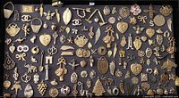 Overview of assorted gold toned pendants, charms, and medallions laid out on dark surface showing various shapes and motifs.