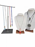 7 vintage Indigenous American beaded necklaces displayed on two busts and a metal necklace stand against white background. Three necklaces hanging on stand are long strands of beads in white, red, and blue colors with beadwork ends. Four necklaces displayed on busts include three beaded medallion necklaces with fringes and one medicine pouch necklace with bead fringe.