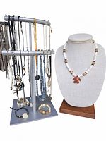Image showing assorted Indigenous American jewelry including necklaces with beadwork and a pendant displayed on a bust and a metal stand with multiple hanging necklaces and bracelets.