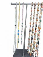 Seven long gemstone necklaces hanging on a silver T-bar fixture, showing a variety of colors and bead shapes.
