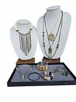 Full lot showing 5 necklaces displayed on busts with 4 bracelets on tray