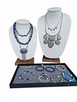 Two necklace display busts showing layered blue bead and silver-tone necklaces, plus tray with various bracelets in blue and silver tones