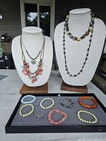 Photo showing full lot of 4 necklaces on busts and 7 bracelets plus 1 pin displayed on table.