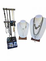 Overall view of the jewelry lot featuring necklaces on busts and bracelets and charms on a metal stand.