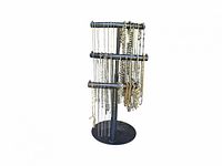 Wide view of jewelry stand displaying multiple silver and gold tone necklaces and bracelets, arranged on three tiers.