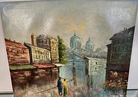 Front view of signed cityscape oil painting showing buildings, domed structures, and two figures walking.