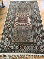 Full view of the antique handmade Iranian wool rug showing overall geometric design and fringe on one end.