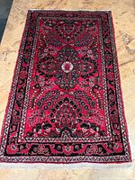 Full view of the deep red Sarough rug with floral motif and detailed borders placed on light floor tiles.