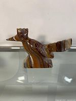 Front view of hand carved woodpecker figurine showing detailed wing and head shape with brown and beige marble stripes.