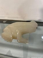 Side view of the crisply carved marble frog figurine showing smooth polish and details of legs and eyes.