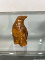 Front view of a hand carved stone penguin figurine with smooth brown polished surface.