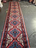 Full-length view of runner showing entire patterned field and borders laid on concrete floor