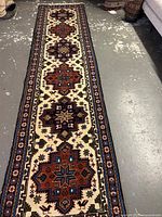 Full length view of runner rug on concrete floor showing overall pattern and minor wear