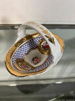 Top angled view showing the detailed floral design inside the candy dish, gold accents, blue diamond lattice pattern, and ornate handle with gold leaf motifs.