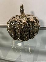 Front angle view of the silver coloured metal decorative pumpkin showing the stem and textured surface with reflective finish.