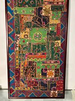 Closer angled view highlighting texture, embroidery details, mirrors, and layering of fabric patches in the vintage patchwork textile artwork.