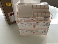 Front view of organizer beside original box and foam, film wrap intact